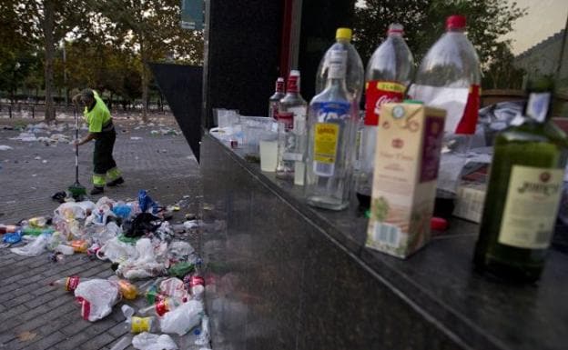 Un operario barre los restos de un botellón en una calle de Valencia.