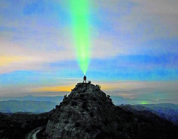A las cinco de la madrugada de un mes de julio en el paisaje desértico de Gorafe, en Granada. El Niño de las Luces aparece subido a una cima. Lleva una linterna frontal de color verde y mira al inmenso horizonte. El tiempo de exposición se prolongó durante 20 segundos. 