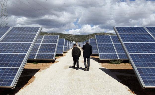 Dos personas recorren un parque solar fotovoltaico de Alicante