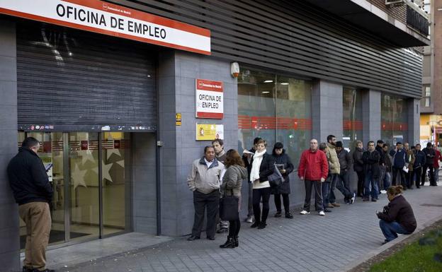 Un grupo de personas haciendo cola ante una oficina de empleo.