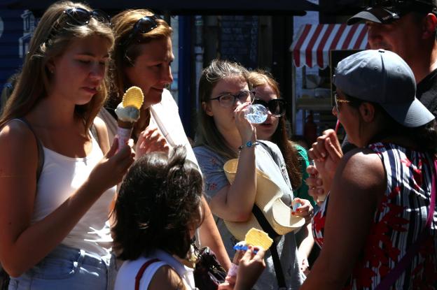 Gente refrescándose con helados y agua. 