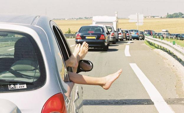 Viajeros airean sus pies en una autopista de Orleans, en Francia, durante la operación salida de vacaciones de verano 