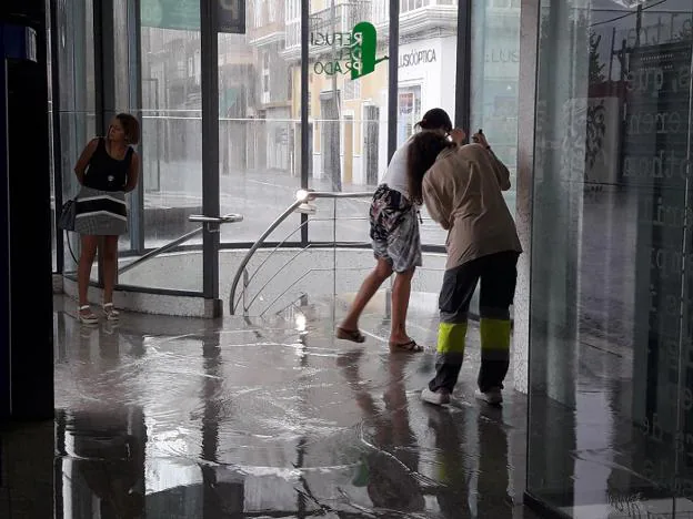 Dos personas achican el agua del parking del Prado de Gandia, inundado por la tromba de agua. 