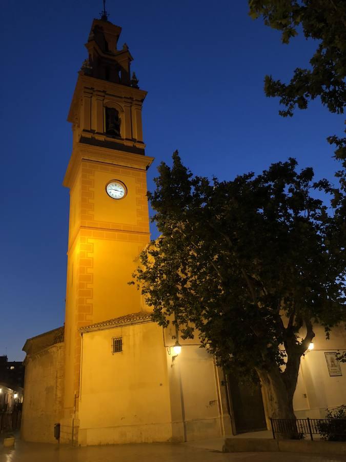 Es una de esas zonas poco conocidas de Valencia. El barrio de Campanar reúne todas esas características que se espera encontrar en un remoto y solitario pueblo, y no en plena urbe. Calles tranquilas, casas antiguas, fachadas con un encanto diseñado por el paso del tiempo. Recorrer sus aceras es pasear por un rincón de paz, ajeno al constante ajetreo de la ciudad. Una especie de paréntesis entre el tráfico, ruido y bullicio, en un lugar donde el reloj parece detenerse, mientras las sombras del atardecer se van colando por cada resquicio. Entre paredes blancas, tonalidades ocre, fuentes y ventanas que se asoman a décadas de historia, permanecen mosaicos en honor a lo que el pueblo fue. Azulejos que recuerdan al oficio hornero y la patrona, la Virgen de Campanar, cuelgan de paredes en las que los ladrillos soportan más años que peso. Casas, unas bajas y otras ilustres, que recuerdan un tiempo no tan lejano, muestras de la Valencia pasada rodeadas de la ciudad actual. 