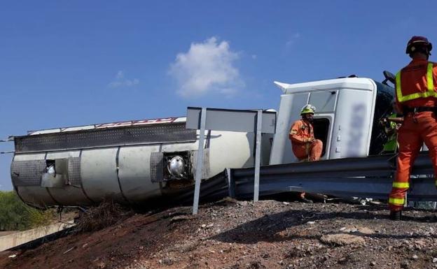 Los bomberos trabajan junto al camión volcado en la A-23.