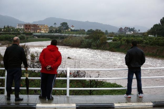 Varios vecinos observan una crecida del río Sellent a su paso por el municipio de Cárcer 