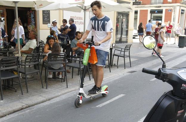 Un joven circula con un patinete eléctrico de alquiler en la calle Colón hace unos días. 