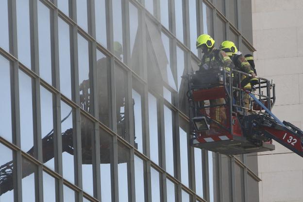 Bomberos junto a la humareda por el grave incendio. 