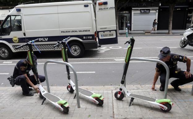 Dos policías realizan mediciones antes de retirar los patinetes de las calles de Valencia