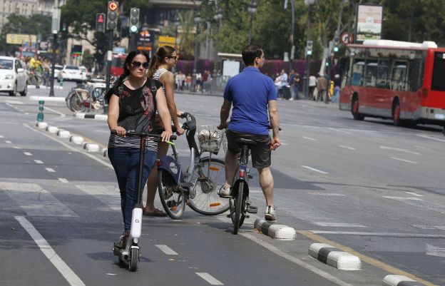 Una mujer circula en patinete eléctrico por Valencia.