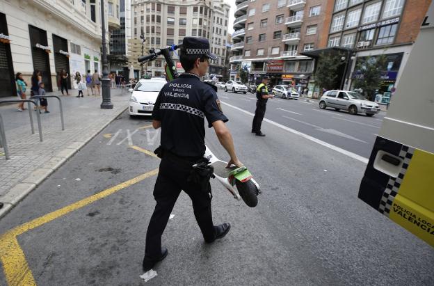 Un agente retira en la calle Xàtiva, ayer, un patinete eléctrico. 