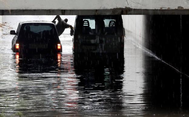 La furgoneta (derecha) que ha quedado atrapada por el agua en Alfafar.