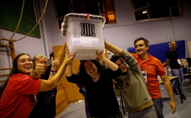 Voluntarios alzando una urna, tras el cierre de su colegio electoral, el dia del referendum catalan del 1-O .