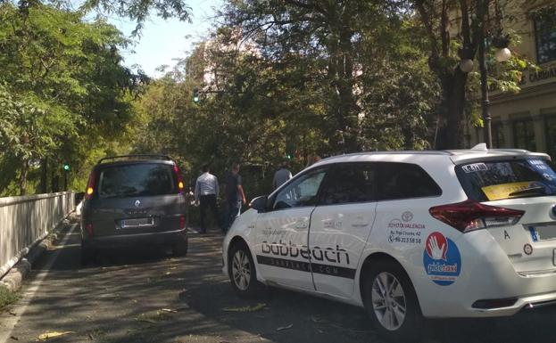 Coches parados ante la caída de la rama frente a la Casa Caridad de Valencia.