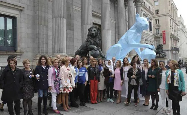 La presidenta del Congreso Ana Pastor posa delante de una leona de cartón, que ha sido colocada en la puerta del Congreso de los Diputados para conmemorar el Día Internacional de la Niña. 