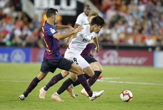 Carlos Soler intenta escapar de la oposición de Busquets y Rakitic. 