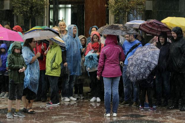 Varias personas esperan cruzar una calle bajo la lluvia ayer en Valencia. 