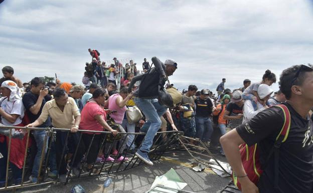 Miles de migrantes hondureños saltan la valla en la frontera de Guatemala para entrar en México, en la orilla del río Suchiate.