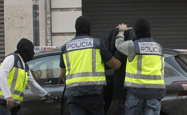 Tres policías con pasamontañas trasladan al hombre detenido en Alaquàs.