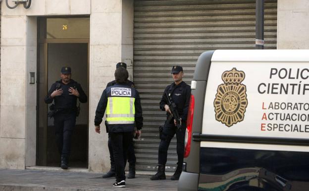 Un grupo de policías en la puerta del edificio donde residía el presunto islamista detenido en Alaquàs. 