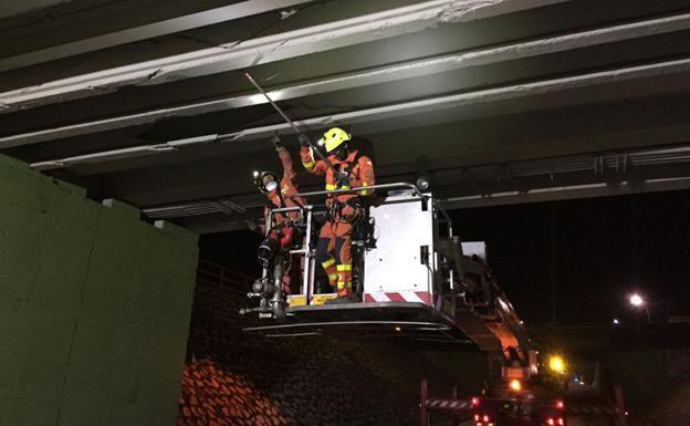 Los bomberos, bajo el puente dañado por el camión de transporte especial en Paterna.