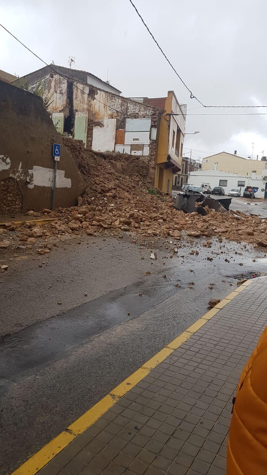 La acumulación de agua en Montserrat durante las últimas horas ha provocado el desprendimiento de tierra en un solar cercano al centro de salud. Este incidente no ha causado daños pero el muro antiguo que se encontraba en este solar ha cedido y la tierra y las piedras han llegado a la calle.