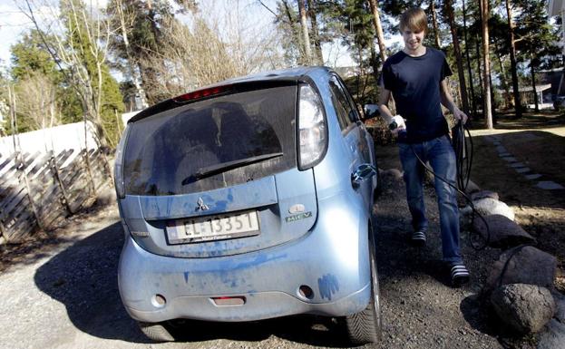 Un joven carga las baterías de su coche eléctrico en un barrio de las afueras de Oslo. 