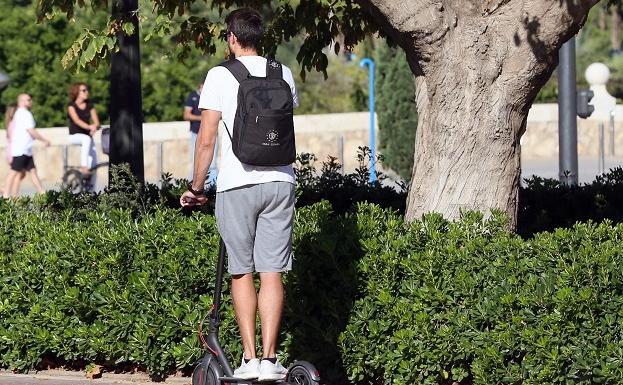 Un joven, en un patinete eléctrico por Valencia.