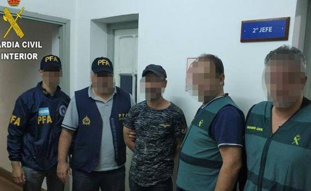 EL presunto homicida con las manos engrilletadas junto a dos policías argentinos y dos guardias civiles. 