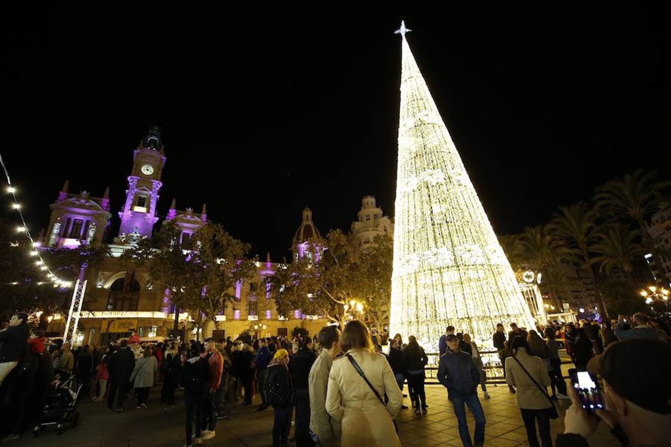 La Plaza del Ayuntamiento de Valencia ha vivido este viernes el encendido oficial de la iluminación navideña. Como gran novedad, este año otros dos barrios y dos pueblos de la ciudad se suman en la apuesta por descentralizar la decoración. Los dos barrios que este año estrenarán árbol de Navidad serán Benicalap y Malilla, sumándose así a las plazas de Patraix, Campanar, Benimaclet, Sant Valer (en Russafa), la Creu del Canyamelar y Doctor Collado (en Ciutat Vella), Orriols, Sant Marcel·lí y Abastos. Serán un total de 11 los árboles que se repartirán por toda la ciudad, además del de la Plaza del Ayuntamiento.