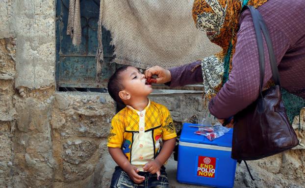 Una mujer suministra la vacuna de la polio a un niño en Pakistán.