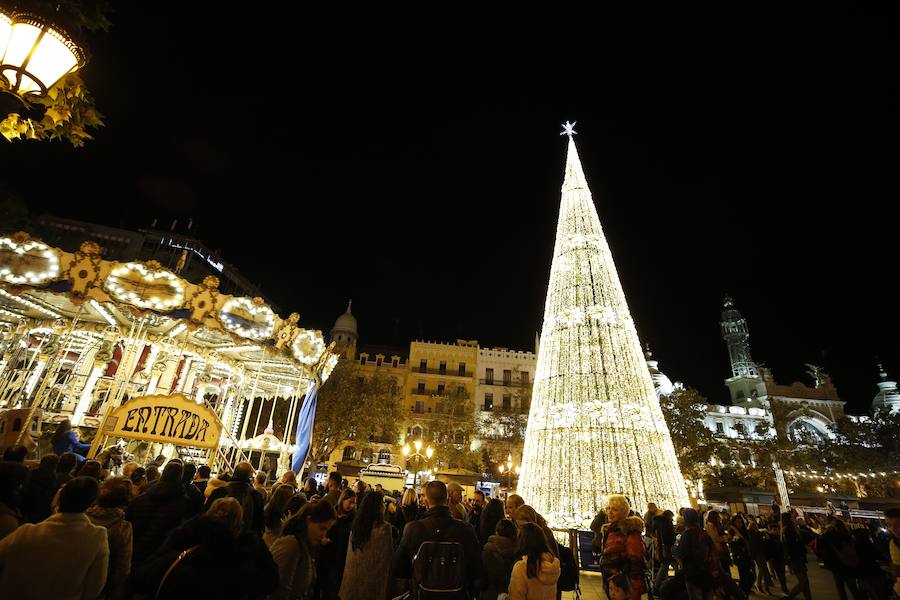 La Plaza del Ayuntamiento de Valencia ha vivido este viernes el encendido oficial de la iluminación navideña. Como gran novedad, este año otros dos barrios y dos pueblos de la ciudad se suman en la apuesta por descentralizar la decoración. Los dos barrios que este año estrenarán árbol de Navidad serán Benicalap y Malilla, sumándose así a las plazas de Patraix, Campanar, Benimaclet, Sant Valer (en Russafa), la Creu del Canyamelar y Doctor Collado (en Ciutat Vella), Orriols, Sant Marcel·lí y Abastos. Serán un total de 11 los árboles que se repartirán por toda la ciudad, además del de la Plaza del Ayuntamiento.