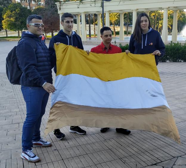 Los deportistas FER posan con la bandera y su creador. 