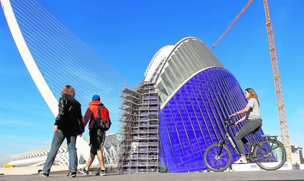 Unos visitantes observan, ayer, los andamios que aún rodean el Ágora de la Ciudad de las Artes y las Ciencias. 