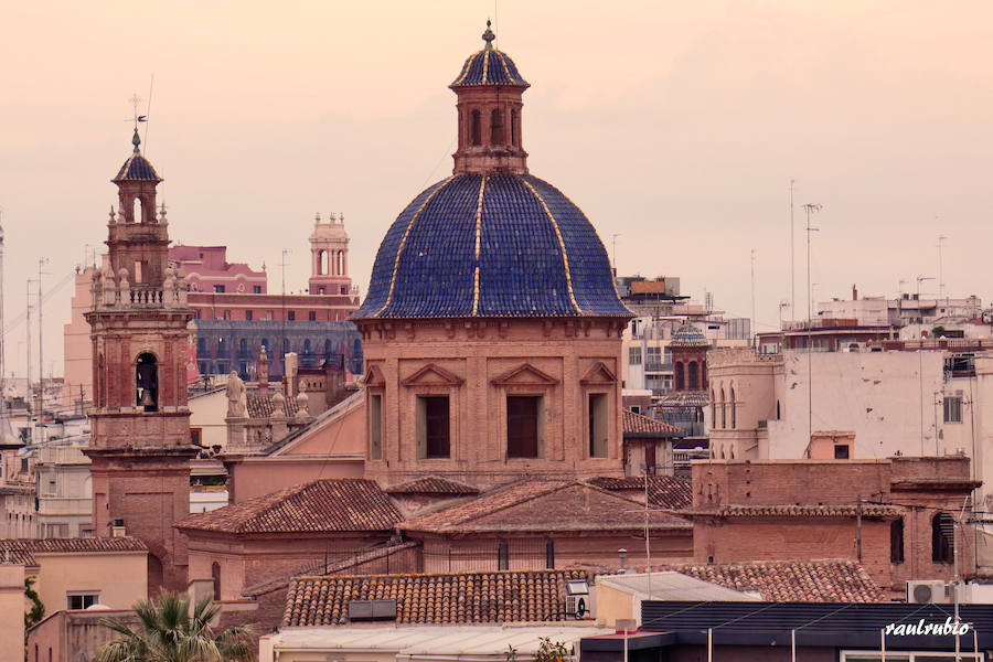 Valencia nunca deja de sorprender. Es habitual la imagen desde la calle de los múltiples campanarios que se encuentran en la ciudad. En el centro histórico aún encontramos más torreones eclesiásticos. Pero, ¿cómo se ve la ciudad desde el cobijo de las campanas?. Raúl Rubio, de la Associació de Mestres Campaners, ha inmortalizado esa visión de la que poca gente puede disfrutar: Valencia desde sus campanarios. Ver la plaza de San Agustín con una perspectiva diferente, contemplar el centro de la ciudad desde Santa Catalina, admirar Valencia desde las campanas del Real Monasterio de la Santísima Trinidad son algunos de las panorámicas exquisitas casi exclusivas para campaneros. La ciudad se redescubre desde las alturas, desde la perspectiva de gárgolas, campanas y tejados. Así es Valencia desde sus campanarios.