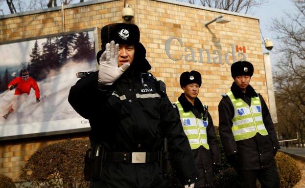 Oficiales de policía chinos custodian la embajada de Canadá en Pekín.