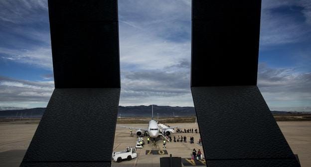 Varios operarios trabajan junto al avión estacionado en la pista del aeropuerto de Castellón. 