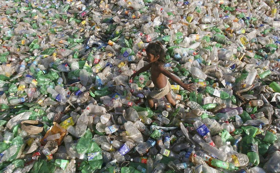 Un niño camina entre los residuos de un vertedero de botellas de plástico de Dhanas (India).