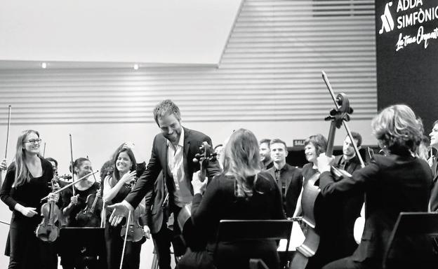 Los miembros de la orquesta bromean con el director durante el ensayo previo a la actuación.