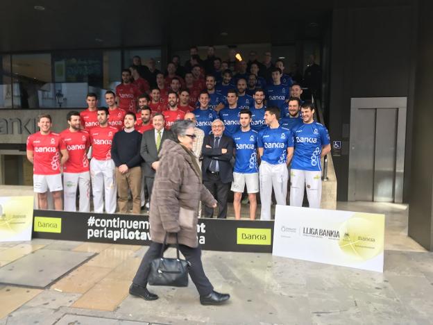 Una mujer pasa mientras posan los pilotaris participantes en la Lliga. 