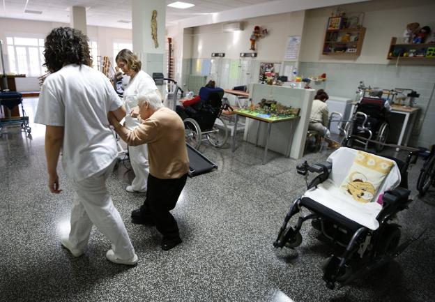 Taller. Dos trabajadoras ayudan a una de las residentes. 