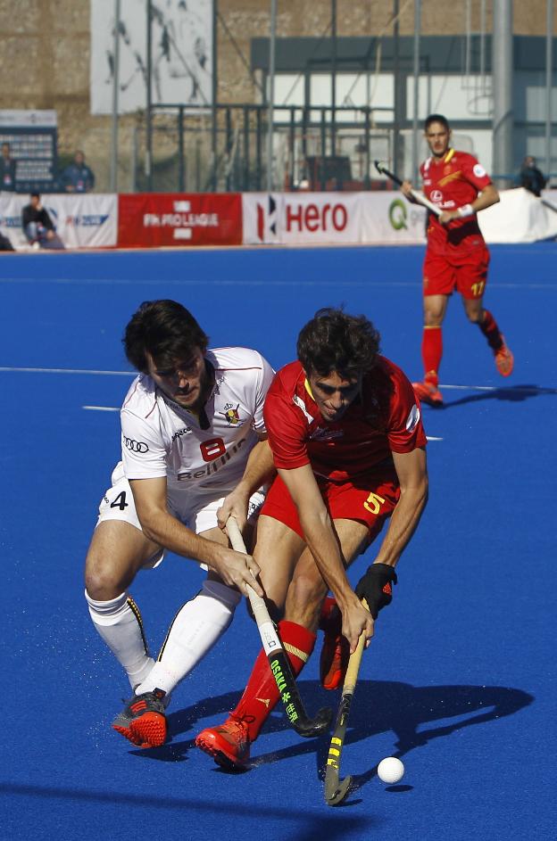 Un jugador español y otro belga pelean por una pelota. 