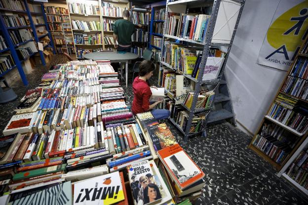 Dos personas consultan títulos impresos en papel  en una librería de Valencia. 