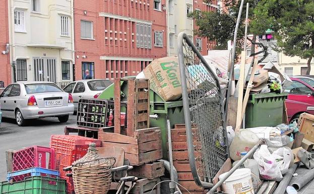 Trastos viejos y basura, junto a un contenedor de residuos orgánicos en una calle de la capital valenciana.