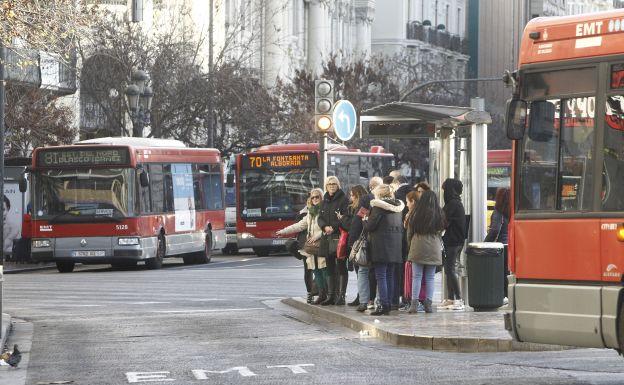 Usuarios de la EMT de Valencia esperando al autobús en una parada de la plaza del Ayuntamiento.