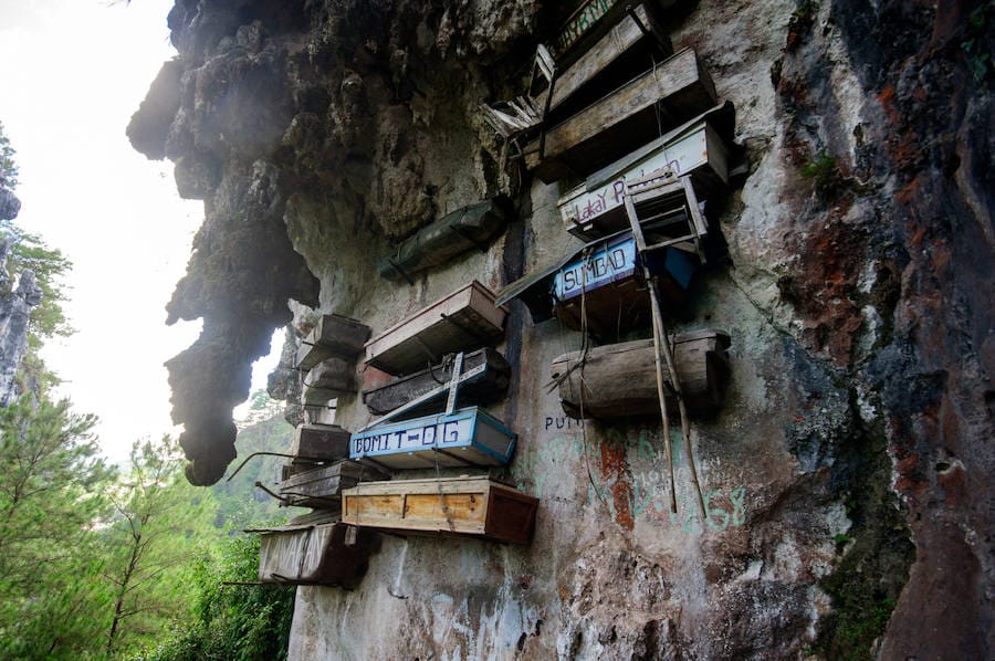 Ataúdes colgantes de Sagada (Filipinas) | En lugar de enterrar a sus difuntos bajo tierra, en esta región cuelgan los ataúdes de acantilados. En un principio se hacía con el objetivo de evitar que los animales pudiesen llegar a los cuerpos, pero con el tiempo se ha convertido en una tradición. Además, se dice que los féretros son tallados por los propios ancianos antes de morir.