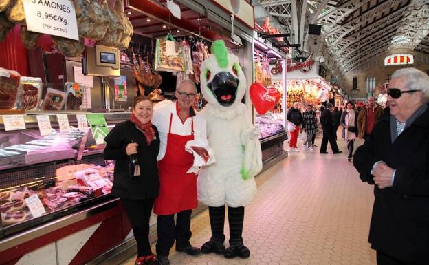 La pareja de vendedores junto a 'Cotorra', la mascota del Mercado Central. 