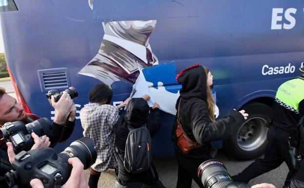 Un grupo de jóvenes arranca por la fuerza los vinilos del autobús. 