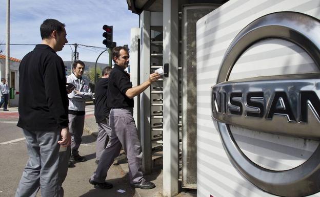 Operarios de una fábrica de coches fichan a la entrada.