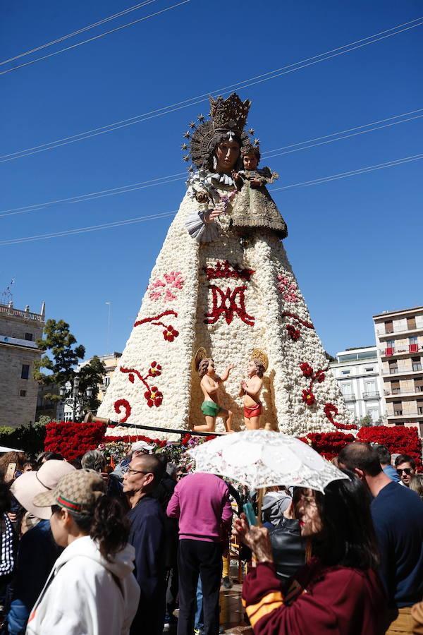 La Ofrenda concluyó este lunes después de que miles de falleros desfilaran para llevar las flores a la Virgen de los Desamparados. Este martes, a la luz del día se ha desvelado ante los ojos de los valencianos el aspecto definitivo del manto de la 'Geperudeta'. Claveles blancos, rojos y rosas componen componen el diseño del vestidor Rafael Chordá. Un floreado manto con el blanco como color predominante y que preside estos días la plaza de la Virgen, ante su basílica.